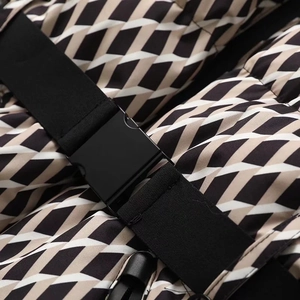 Detail of winter ski jacket showing adjustable nylon belt and buckle on patterned fabric