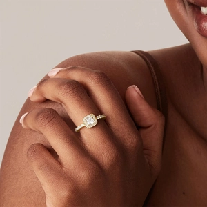 Macro shot of a luxury gold engagement ring featuring a square-cut halo diamond on finger