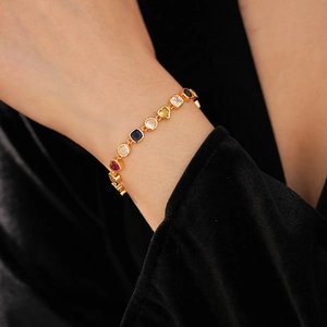 Détail d'un bracelet vintage doré avec zircons colorés en forme de cœur et géo