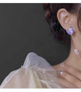 Gros plan d'une boucle d'oreille cœur marbré violet avec placage d'or sur le côté
