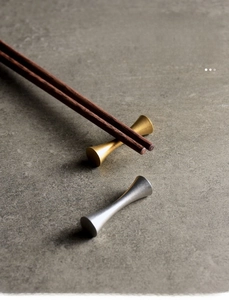 Macro shot of minimalist gold and silver stainless steel chopstick rests on stone