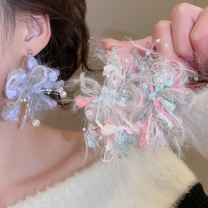 Detail of plush flower earrings with pearls shown on model and in hand close-up