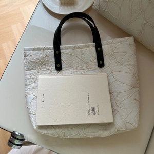 Close-up of leaf embroidery on cream canvas tote bag with black leather strap
