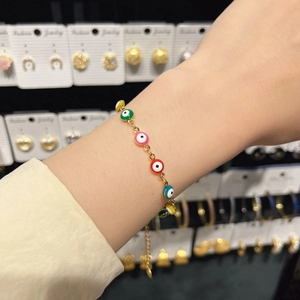 Close-up of gold adjustable evil eye bracelet with colorful enamel beads on a wrist
