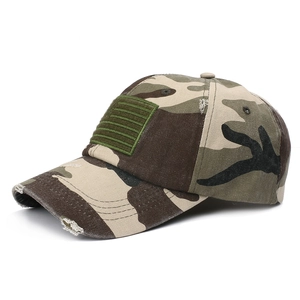 Detail of distressed camouflage baseball cap with green flag patch and vintage ripped texture