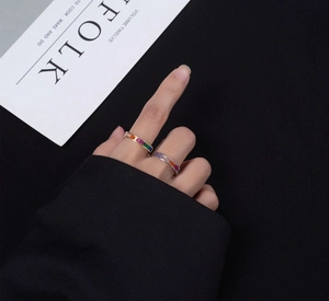 Close-up of gold and silver S925 rings with rainbow colored gemstones on a hand