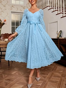 Détail de la robe en dentelle bleu clair avec nœud à la taille et motifs floraux