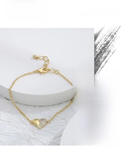 Macro shot of gold heart bracelet with sparkling cubic zirconia on white stone background