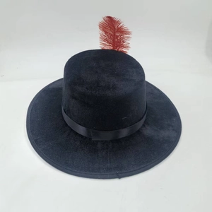 Detail of a vintage black flat top wool felt hat featuring a striking red feather accent