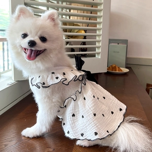 Detail of dog dress featuring black heart patterns, ruffled hem, and black ribbon bow