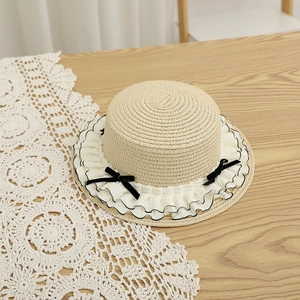 Detail of light beige straw hat with delicate white lace trim and black velvet bow accent