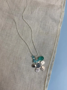 Detailansicht silberner Blumenanhänger mit blauen Perlen und tropfenförmigem Edelstein