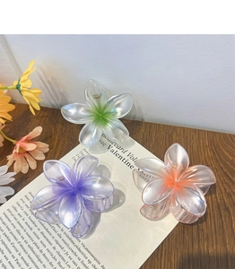 Detailed view of translucent flower hair claws in iridescent green, purple and orange hues