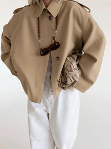 Close-up detail of khaki short trench coat featuring classic lapels and shoulder epaulettes