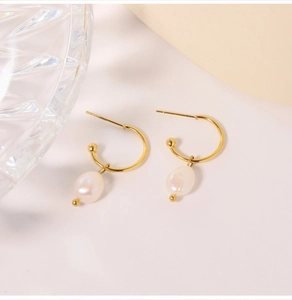 Detail of C-shaped gold-plated earrings with natural white irregular pearls