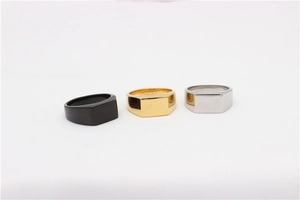 Close-up of three square signet rings in matte black, shiny gold, and silver finishes