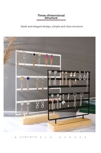 Detail of multi-layered metal jewelry stand with holes and a natural wooden base