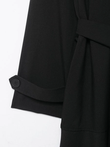 Detail view of black midi dress showing sleeve cuffs, resin buttons, and waist tie belt