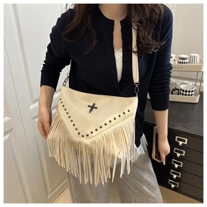 Detail view of cream white PU leather crossbody bag featuring metal studs and fringe accents