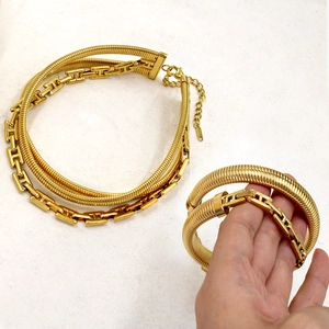 Detail view of gold layered snake chains with H-shaped link and marble background