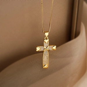 Detailed macro of 18K gold plated cross pendant with zircons and heart shape accents