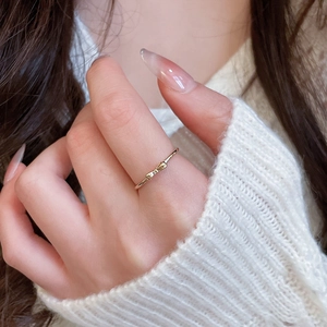 Close-up of minimalist gold bow ring worn on finger with soft knit sweater background