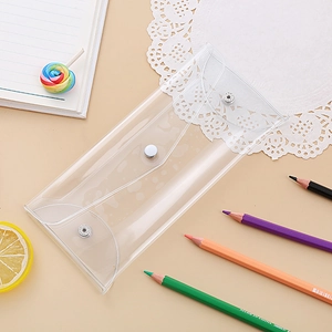 Flat lay of a transparent PVC stationery pouch with a silver snap button on a desk
