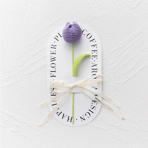 Detail of hand-knitted purple tulip flower tied with a Love Is Eternal ribbon bow
