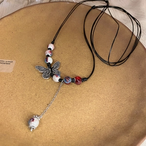 Close-up of a woven ceramic necklace with silver butterfly pendant and ink-patterned beads