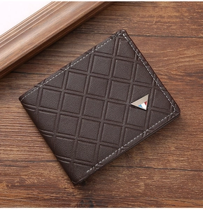 Detail of a brown quilted leather wallet with a triangular metal logo on a wooden desk