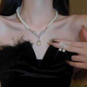 Elegant pearl necklace and teardrop earring set with diamond accents on a model
