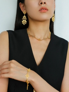 Detailed view of model wearing gold hollow floral necklace, earrings, and bracelet set