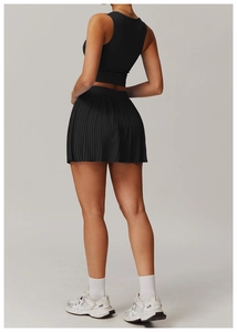 Detail view of black pleated athletic skirt and back of cropped sports tank top