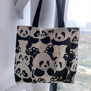 Detail of the panda printed canvas tote bag featuring durable black strap handles