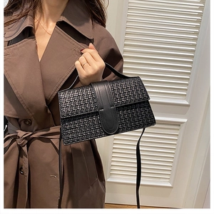 Detail of elegant black woven texture on rectangular crossbody bag with smooth leather strap
