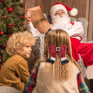 Mädchen trägt eine Weihnachtsschleife mit Pailletten vor festlichem Hintergrund