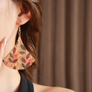Detailed close-up of fan-shaped leaf print cork earrings on a professional model