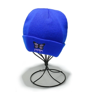 Détail du bonnet en tricot avec broderie papillon violet et inscription DREAMS
