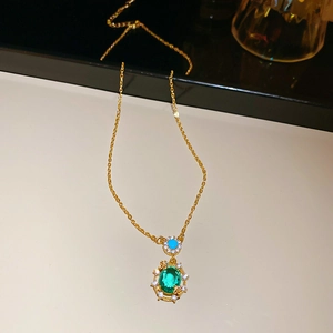 Close-up of 18k gold-plated necklace with oval green gem and blue stone pendant