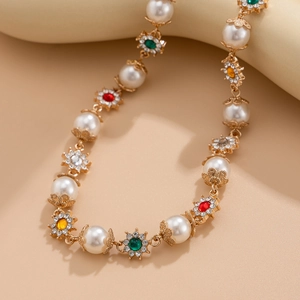 Détail d'un collier doré avec perles blanches et pendentifs floraux en pierres colorées