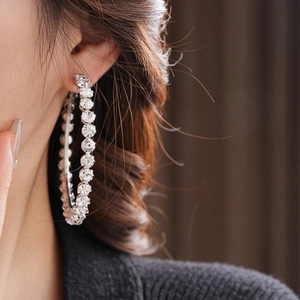 Close-up of a large silver hoop earring with sparkling crystals on a female model