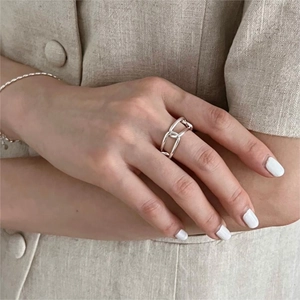 Detail of 925 sterling silver geometric chain ring and bracelet worn on minimalist linen