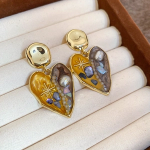 Detail of vintage heart earrings with gold trim, pearls and enamel in a jewelry box
