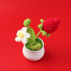 Macro detail of handcrafted crochet strawberry potted plant with red yarn and white flower