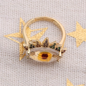 Detail shot of a golden evil eye ring with multi-colored gems and a crown motif