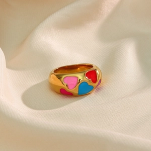 Close-up of golden 18k plated ring with colorful enamel heart patterns on silk fabric