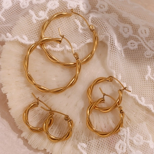 Three pairs of twisted gold hoop earrings in different sizes on a white display
