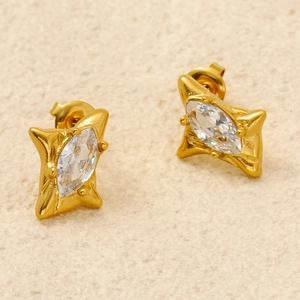 Vue macro de boucles d'oreilles vintage dorées avec zircons sur un fond texturé