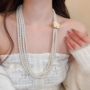 Detailed view of layered pearl necklace with elegant diamond-encrusted camellia flower charm
