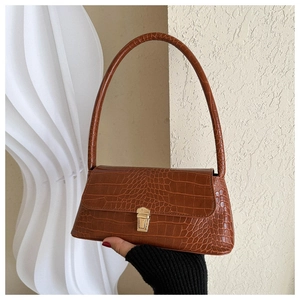 Close-up of brown crocodile texture and gold metal buckle on vintage baguette bag
